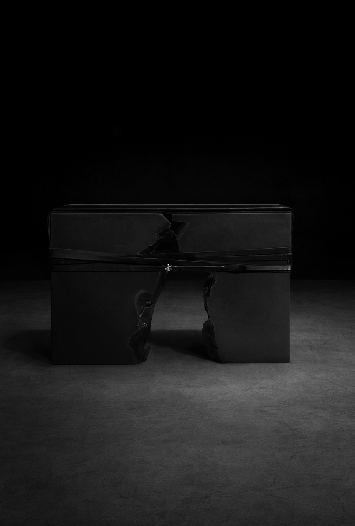Monolithic fractured stone bench by sculptor Isac Elam Kaid bound with leather and silver hardware in a minimal studio setting.