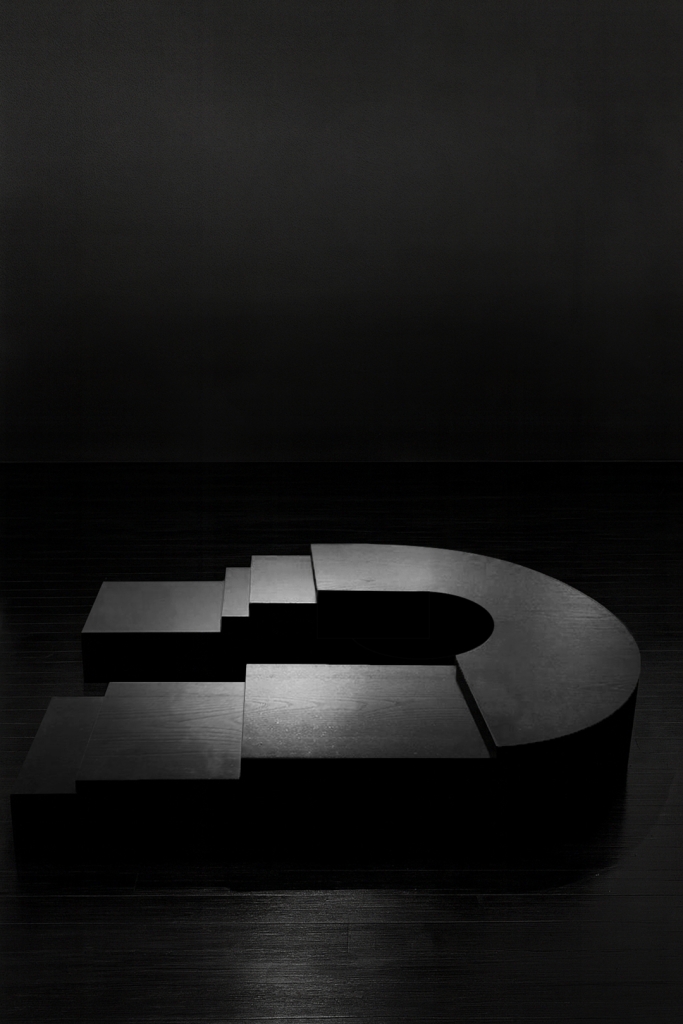 K2505 sculptural ebonized wood table by Isac Elam Kaid, a monolithic low table composed of laminated timber layers forming a stepped architectural mass.