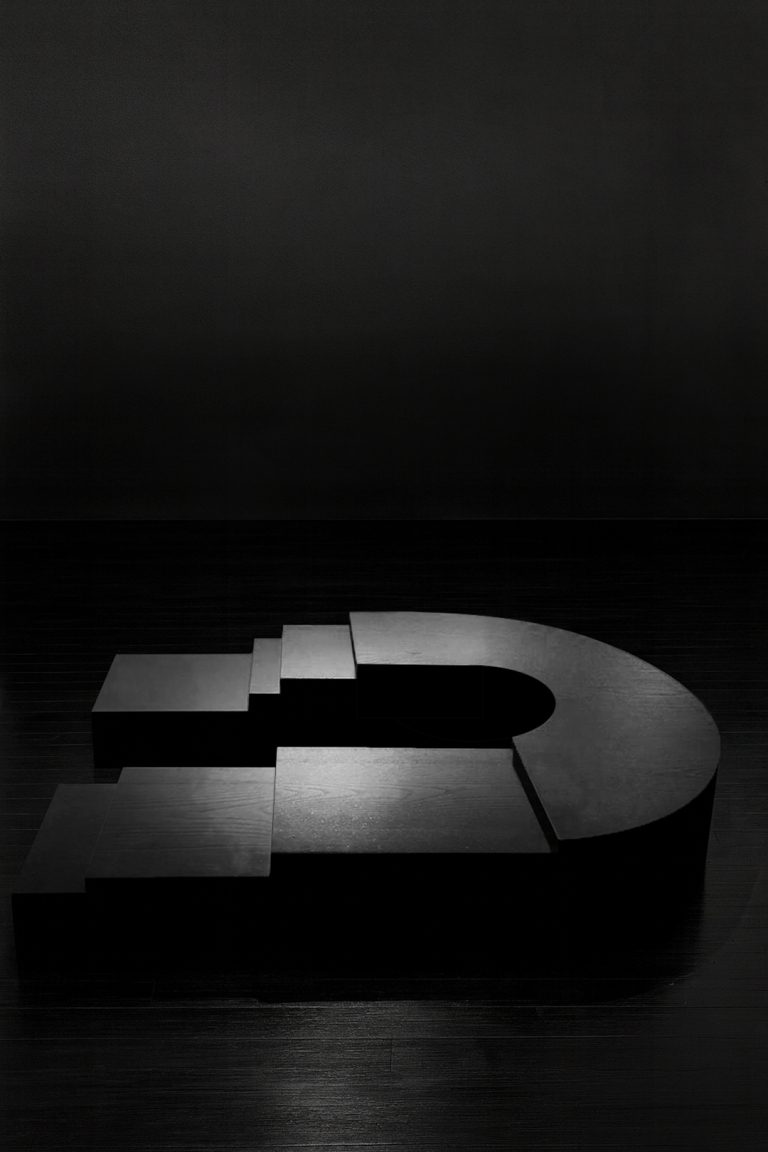 K2505 sculptural ebonized wood table by Isac Elam Kaid, a monolithic low table composed of laminated timber layers forming a stepped architectural mass.
