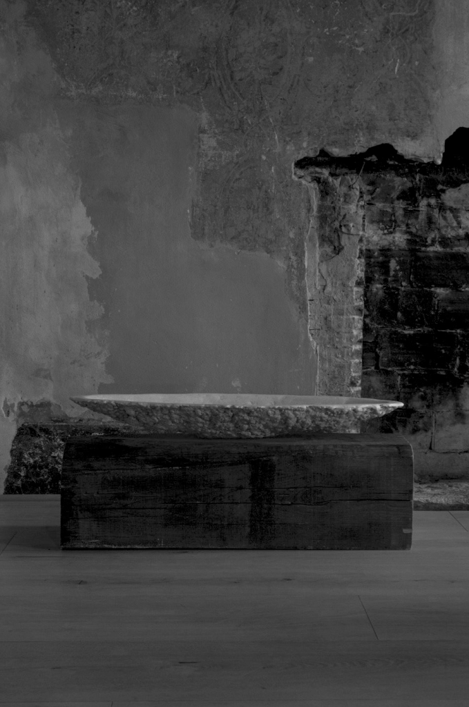 Large sculptural stone vessel by Isac Elam Kaid with eroded perimeter and shallow interior basin.