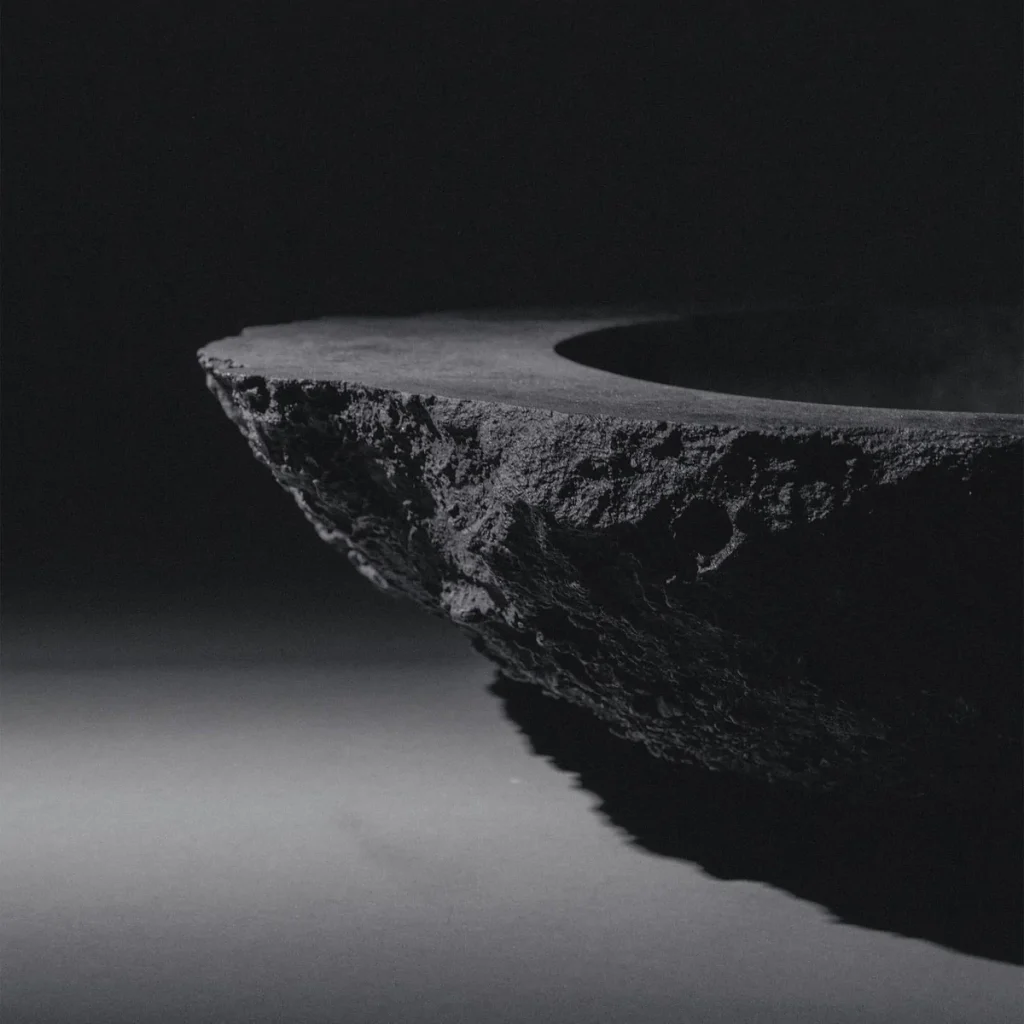 Blackened bronze sculptural vessel by Isac Elam Kaid with irregular eroded edge and circular basin form.